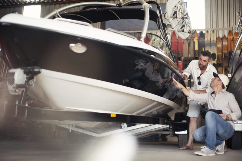 Two men inspecting a boat in a workshop.